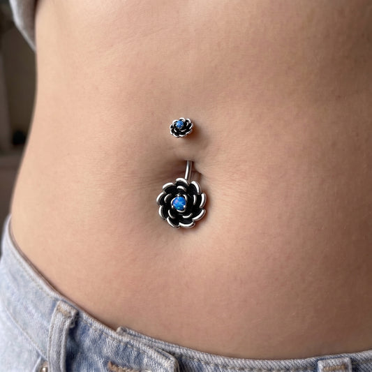 A blue opal flower belly button ring in the piercing of a female model.