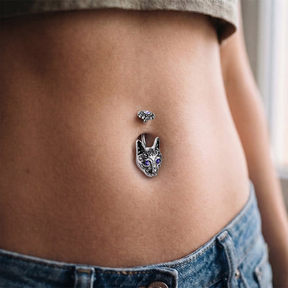 An antique silver tribal cat head belly button ring in the belly piercing of a female model.