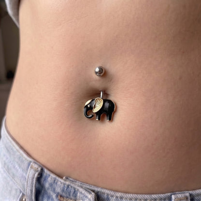 A black and gold elephant belly button ring in the belly piercing of a female model.