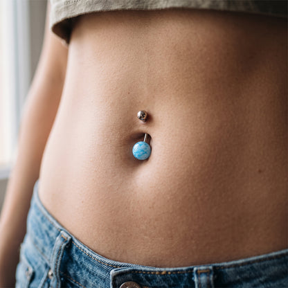 A blue cracked synthetic acrylic stone in the belly button piercing of a female model.