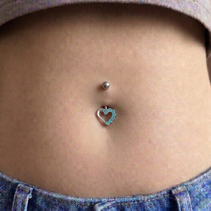 An aqua gem hollow heart belly button ring pictured in the belly button piercing of a female model.