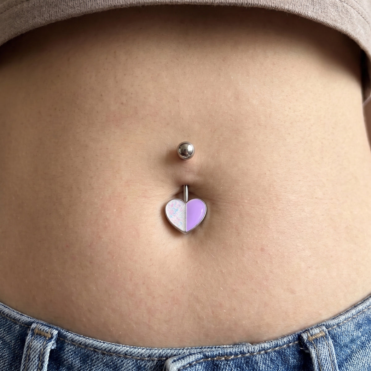Two tone heart belly button ring with purple and white on a female model.